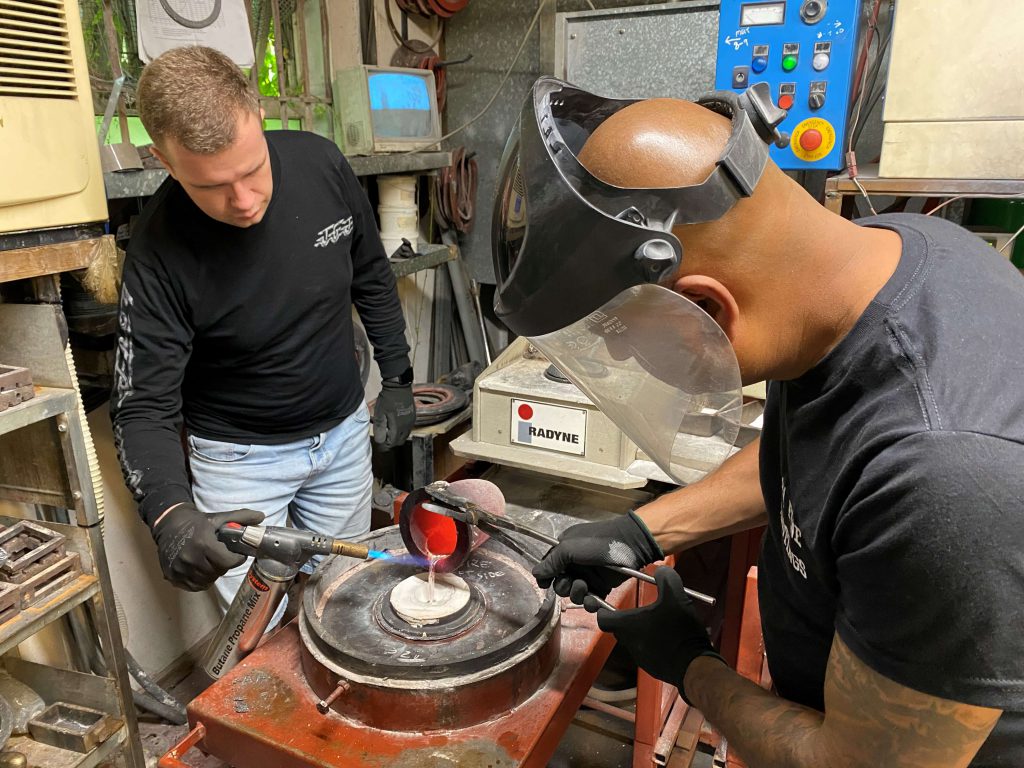 Men handling hot liquid created from melting down Army mess tins