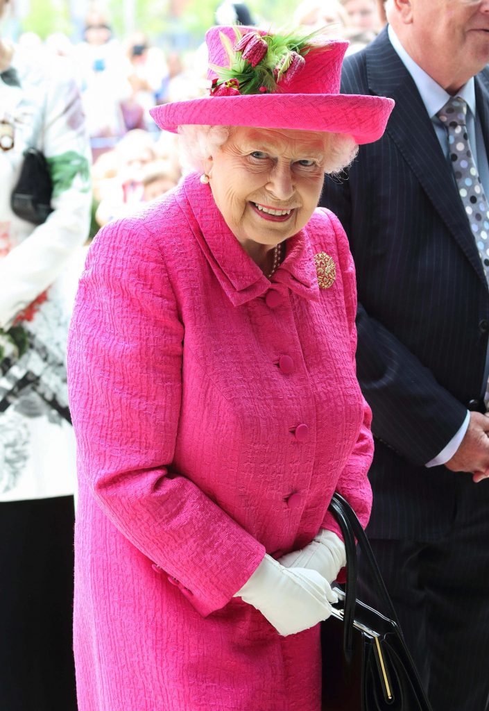 Her Majesty Queen Elizabeth II is a pink jacket and matching pink hat. 