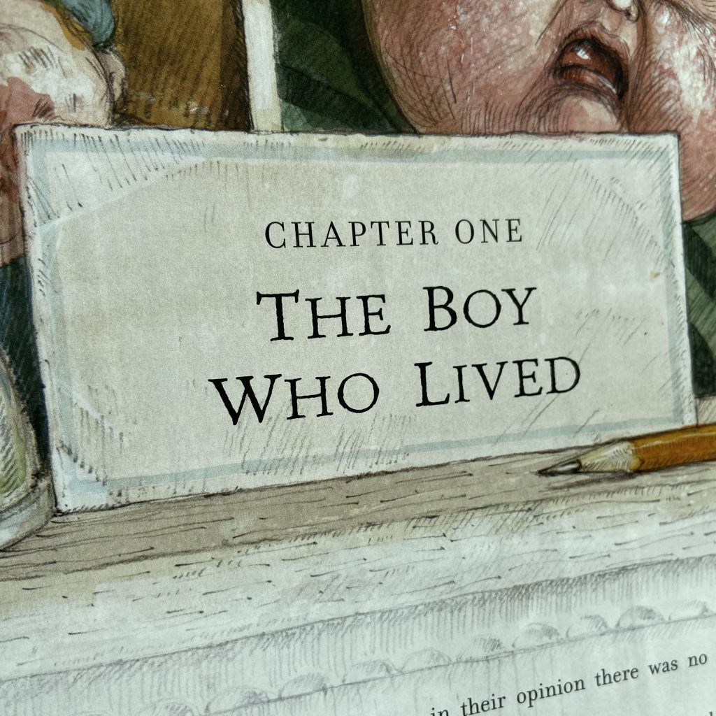 Chapter One of Harry Potter and the Philosopher's Stone in the 2015 illustrated edition by Bloomsbury and Jim Kay. Reads: 'CHAPTER ONE - THE BOY WHO LIVED'